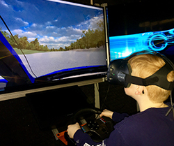 boy wearing virtual reality goggles drives a simulator