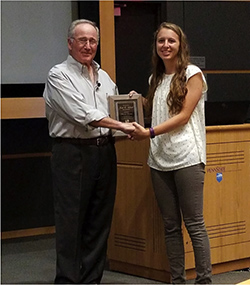 Female student is presented with a fellowship award.