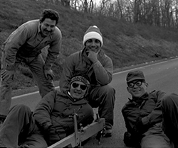 black and white photo of four men on a road surface
